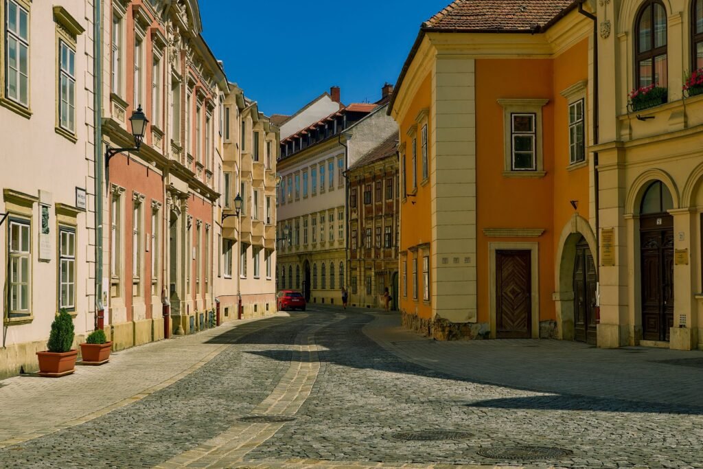 A cobblestone street lined with pastel colored buildings under a blue sky